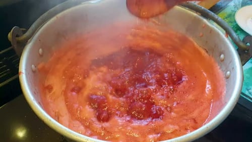 Bright Red Strawberry Jam Simmering on Stove