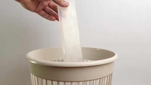 E32 1Plastic packaging is thrown into the trash can. Disposal of household waste.