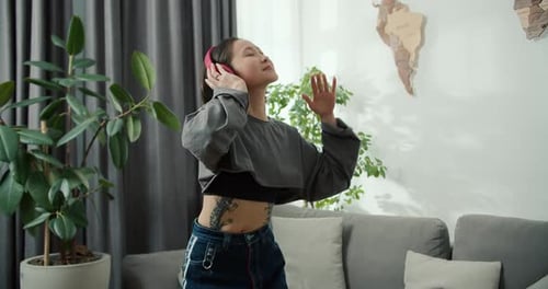 Energetic Woman Dancing with Headphones in Living Room