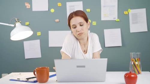 Une femme qui regarde un ordinateur portable est démotivée et s'ennuie.