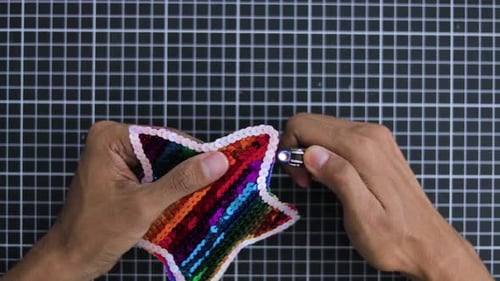 Fabriquant à la main une étoile à paillettes colorées avec un motif arc-en-ciel sur un fond de grille