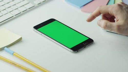 O designer está usando o celular com tela verde no modo retrato.