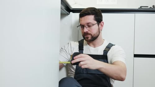 Man Measuring Cabinet with Tape Measure