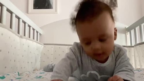 Bebé afroeuropeo de 6 meses en su cuna con un cuerpo gris