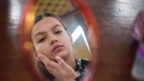 Young Woman Applies Cream to Her Face