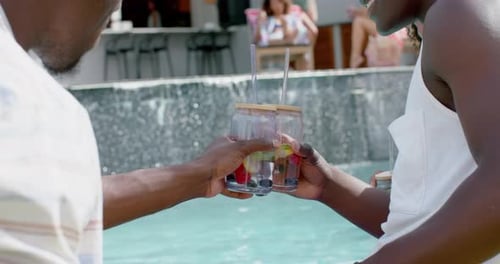 Friends Toasting Drinks by Tropical Swimming Pool