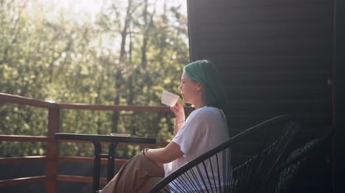 Young Woman Relaxes with Coffee on Porch of Modern Wooden House Tea on Terrace
