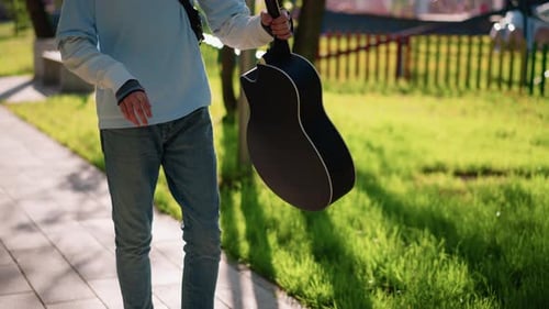 Music in City Urban Street Musician Carrying Guitar in Peaceful Park Setting Relaxed Guitarist
