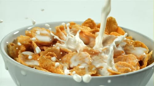 Milk Pouring Over Bowl of Golden Cornflakes