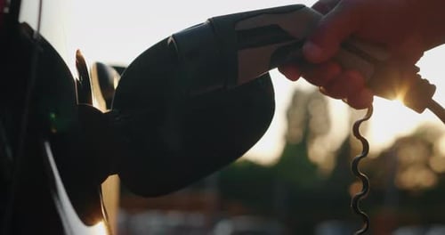 Slow motion close up of power supply plugged into an electric car for charging a modern battery wh