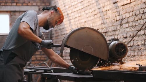 worker cuts metal on a circle and a circular saw. steel pipes and cylindrical blanks for welding.