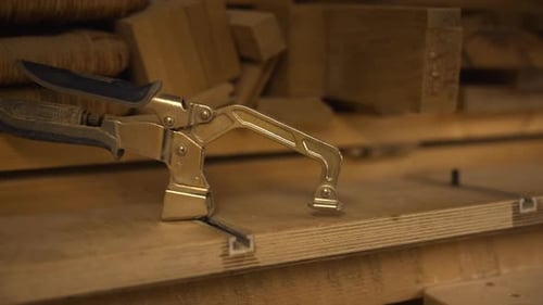 Environnement ciblé mettant en valeur un savoir-faire artisanal avec des pinces maintenant les planches de bois en place