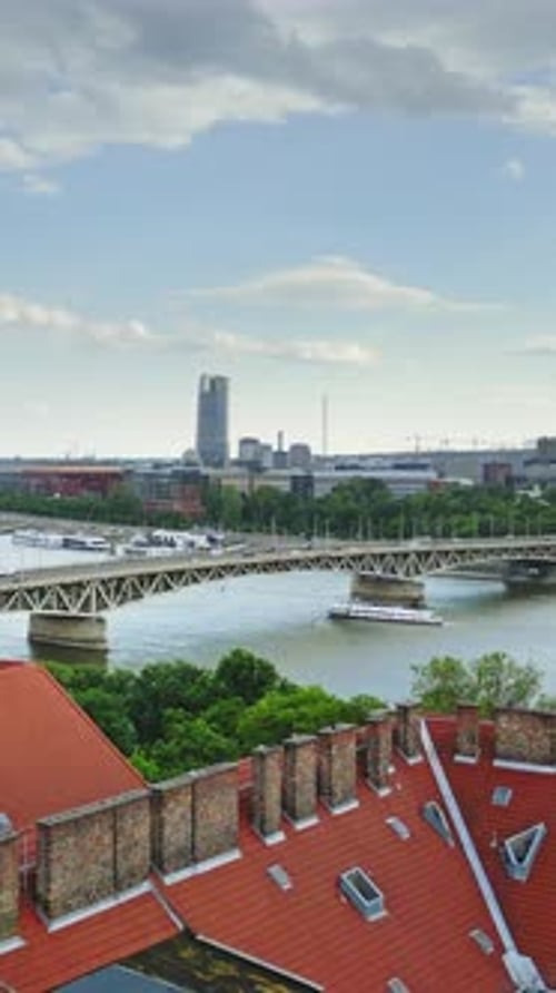 Vertical aerial drone shot over Budapest, capturing the Danube River with a busy bridge filled with