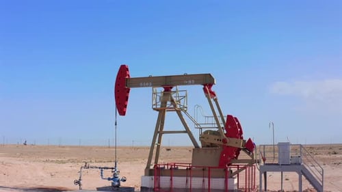 Drone Moving Away From Oil Pumpjack in Desert Oilfield