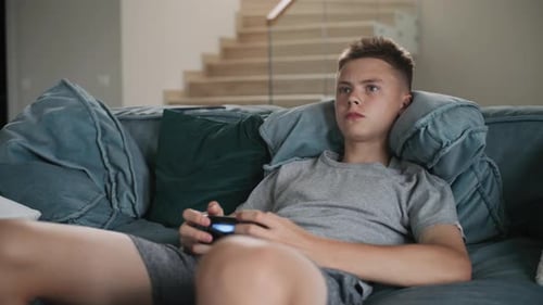Teenager Relaxing and Playing Video Games at Home