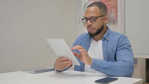 African Businessman Using Digital Tablet in Office