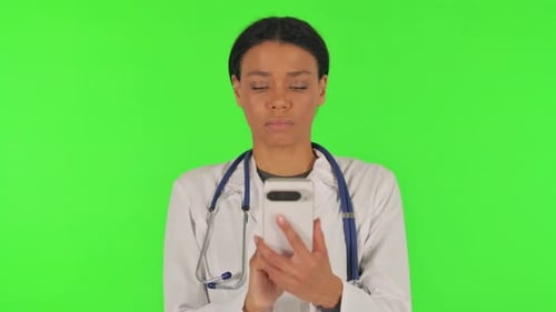 Portrait of Female Doctor Browsing phone on green background