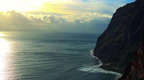 Footage of a cliff next to the sea and the horizon on the background in a sunny day with some clouds