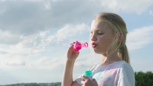 Kind bläst bunte Seifenblasen an einem sonnigen Tag im Freien