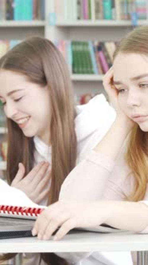 Exhausted Teenage Girl Feeling Bored While Studying in a Bustling Library
