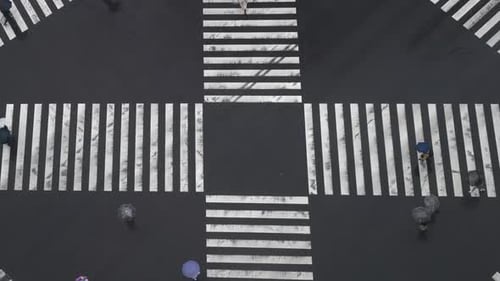 4K Высокий угол обзора: толпа людей, пересекающих пешеходный переход в Токио, Япония, в дождливый день