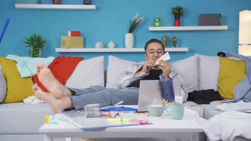 Man Making Paper Airplane on Sofa Indoors