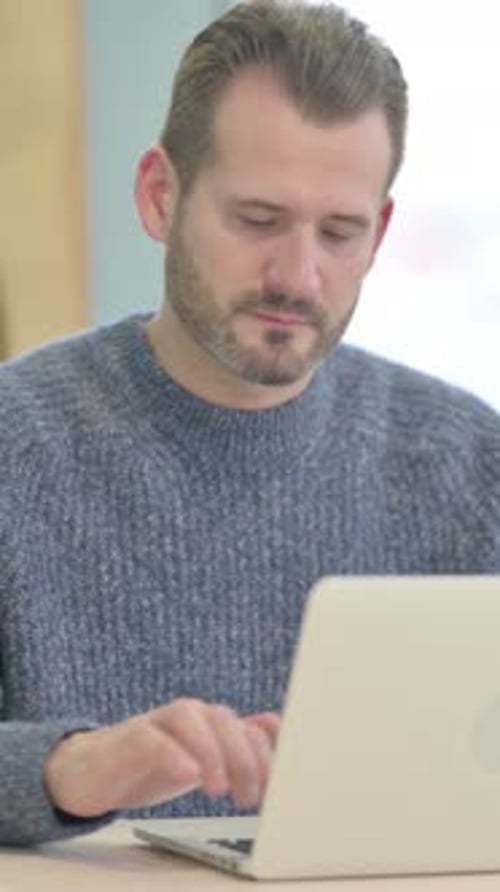 Smiling Man Typing on Laptop Gives Thumbs Up