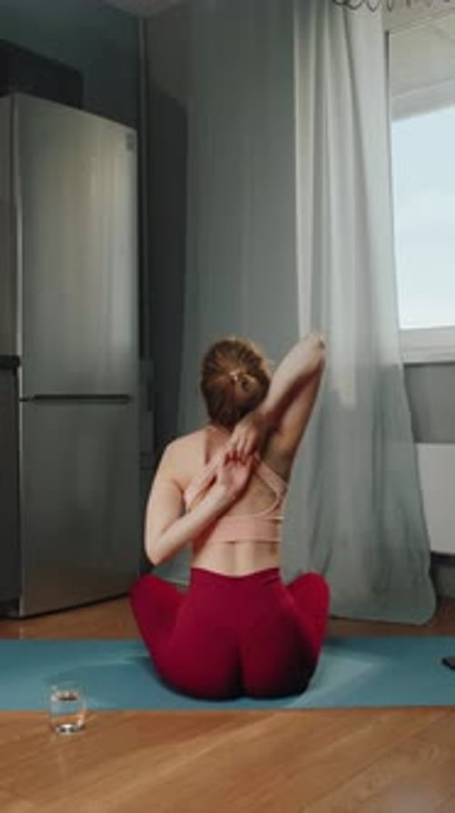 Woman Stretching Arms Overhead on Yoga Mat Indoors