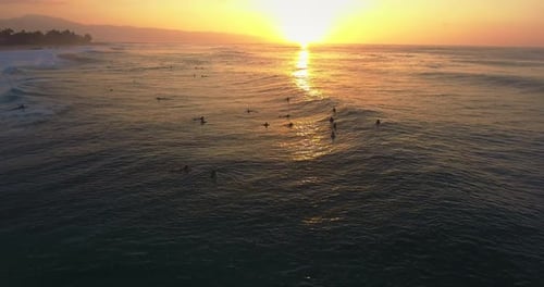 Sunset over group of surfers in Hawaii,