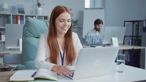 Female Secretary with Headphones and Microphone Solving Client's Problem While Working on Laptop in