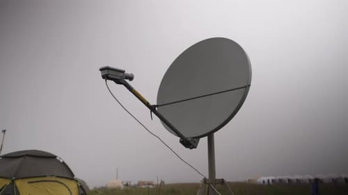 A Satellite Dish Against the Backdrop of a Gray Overcast Sky in a Tourist Camp