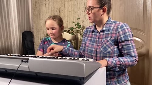 Teacher Helps Child Play Piano at Home