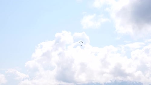 Fallschirmjäger am Himmel auf einem bunten Fallschirm, der zwischen Wolken fliegt, sonniger Tag