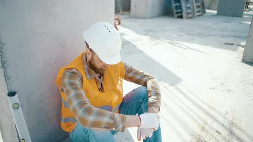 Young foreman sitting outdoors and feeling tired after overwork