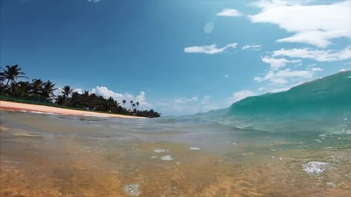 Ocean wave breaks over the sandy tropical beach