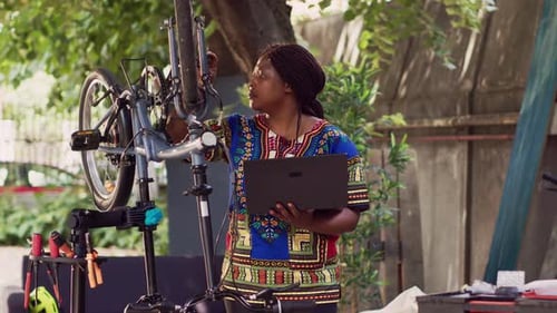 Woman Servicing Bicycle with Laptop