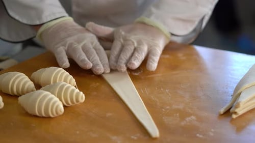 Person Rolling Croissant Dough on Wooden Table