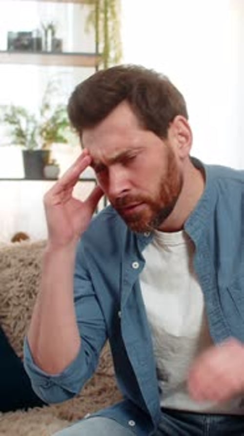 Man Rubs Temples Experiencing Headache Indoors Portrait