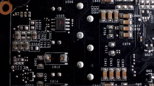 A close-up of the rear side of a graphics card reveals the PCB, a slender platform accommodating var