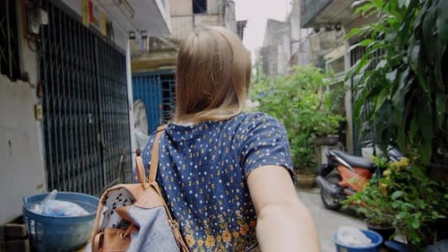 Jovem casal de mãos dadas, turista loira, liderando o namorado andando pela rua asiática de Bangkok...