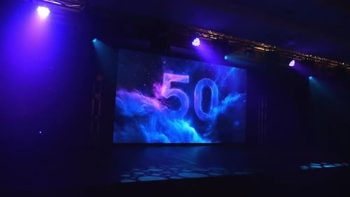 An Empty Concert Stage with a Large Screen with the Number 50 and Floodlights