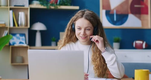 Woman with Headset Working on Laptop at Home