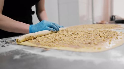 the process of making cinnabons, a woman baker uses chocolate in granules for baking