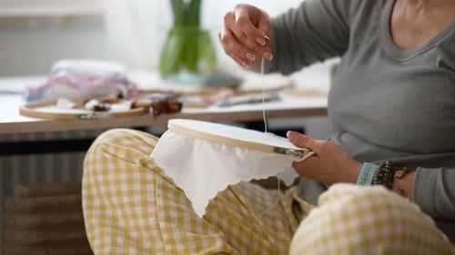 Frau kreiert ein Stickmuster an einem Basteltisch