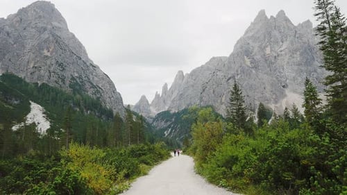 Hiking trip, Dolomites landscape. Pair of tourists is walking along a wide trail in the Dolomites.