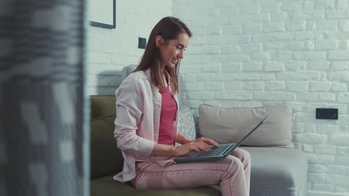 Woman Sitting on Couch Using Laptop Computer