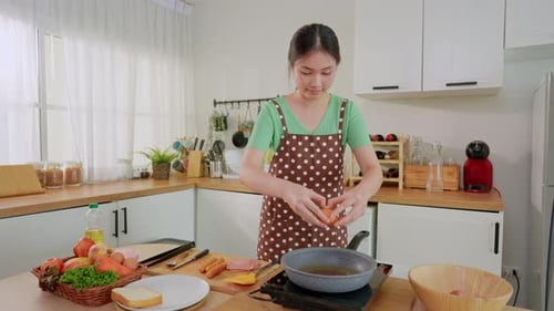 Woman Cracking Eggs in Sunny Kitchen for Cooking