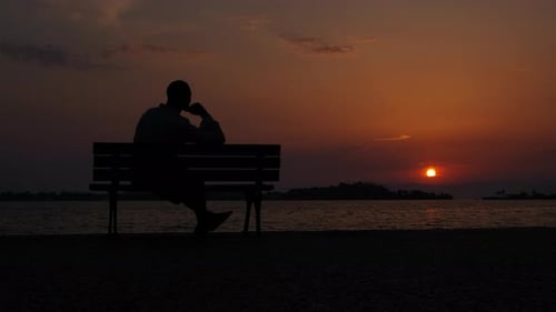 Depressed man sitting against sea.