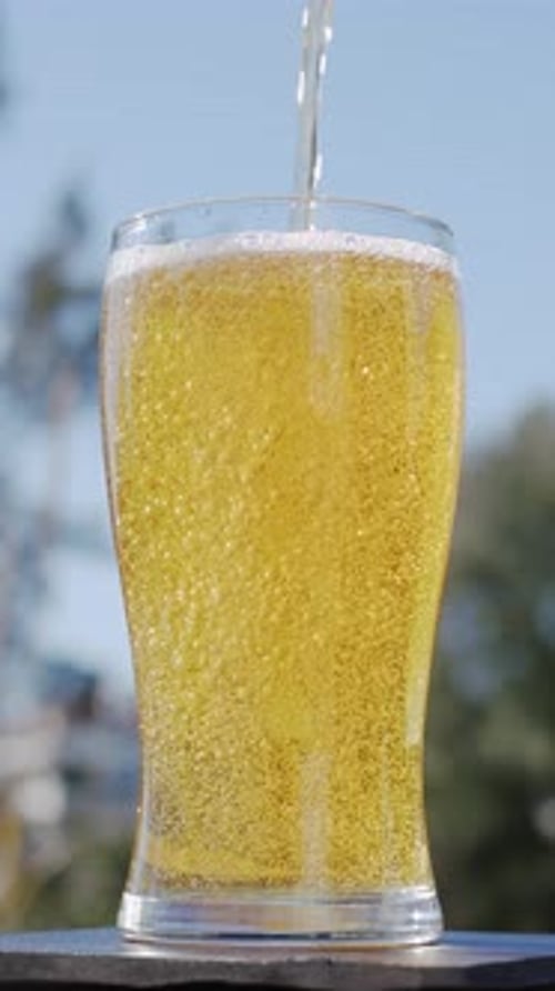 Refreshing Glass of Beer Being Poured on Sunny Day