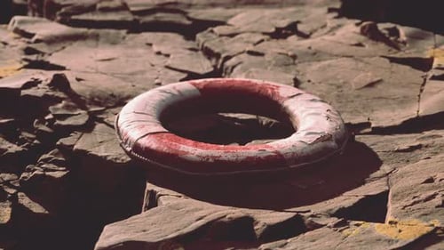 Worn Red Lifebuoy on Rough Rocky Shore